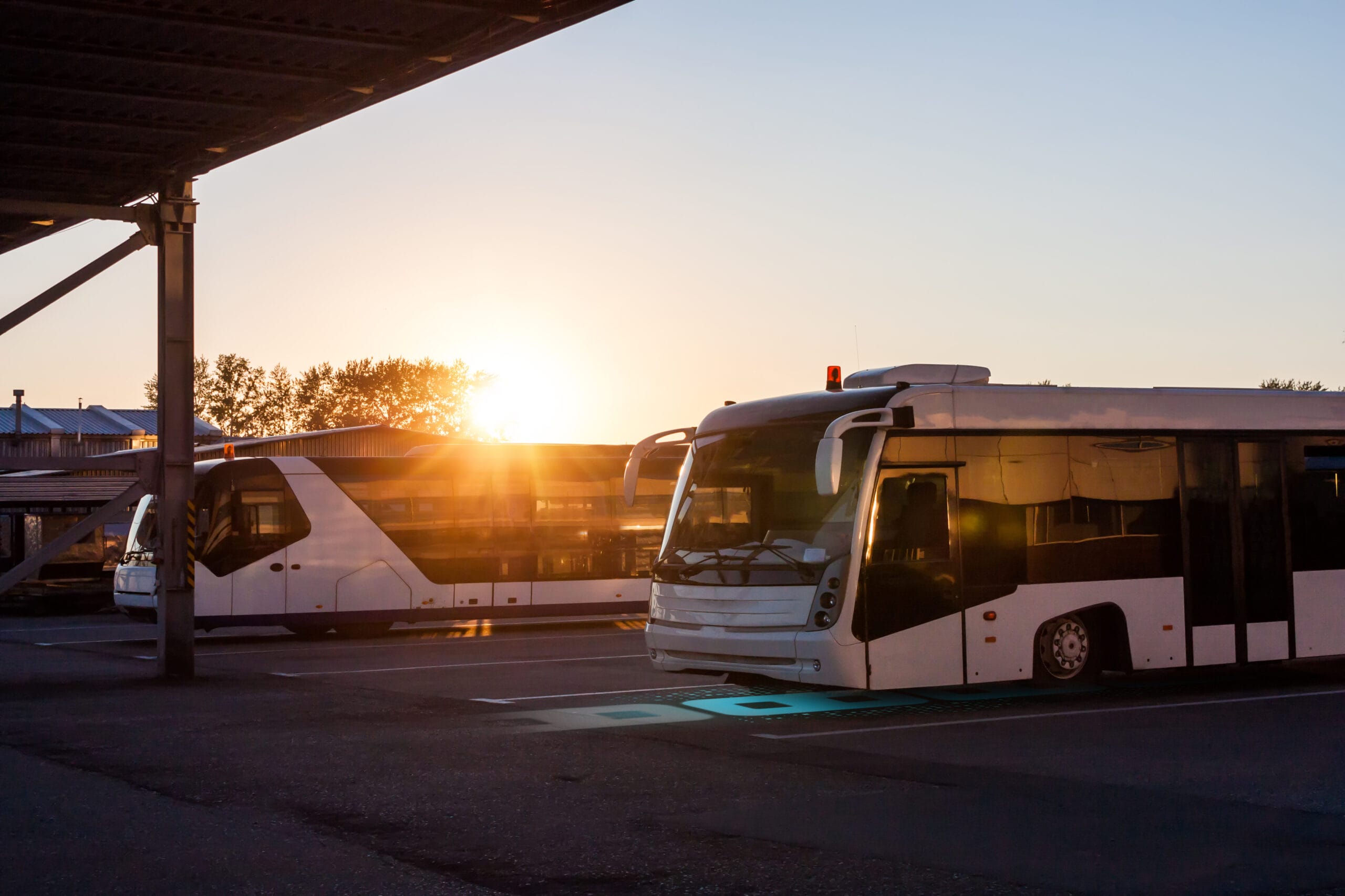 Shuttle buses at the parking lot of the airport in the rays of the setting sun