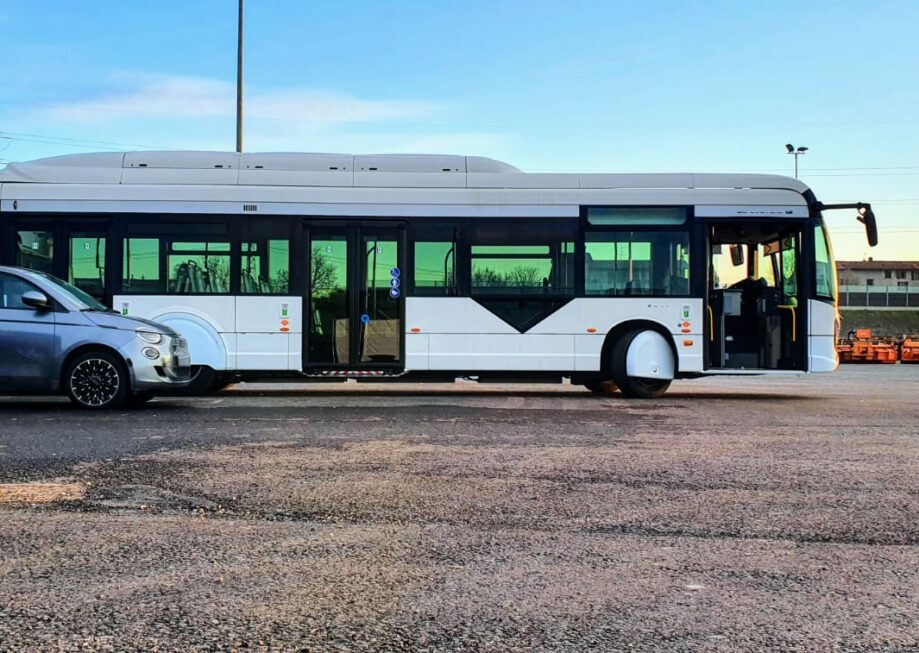 Electric bus side by side with vehicle in green city