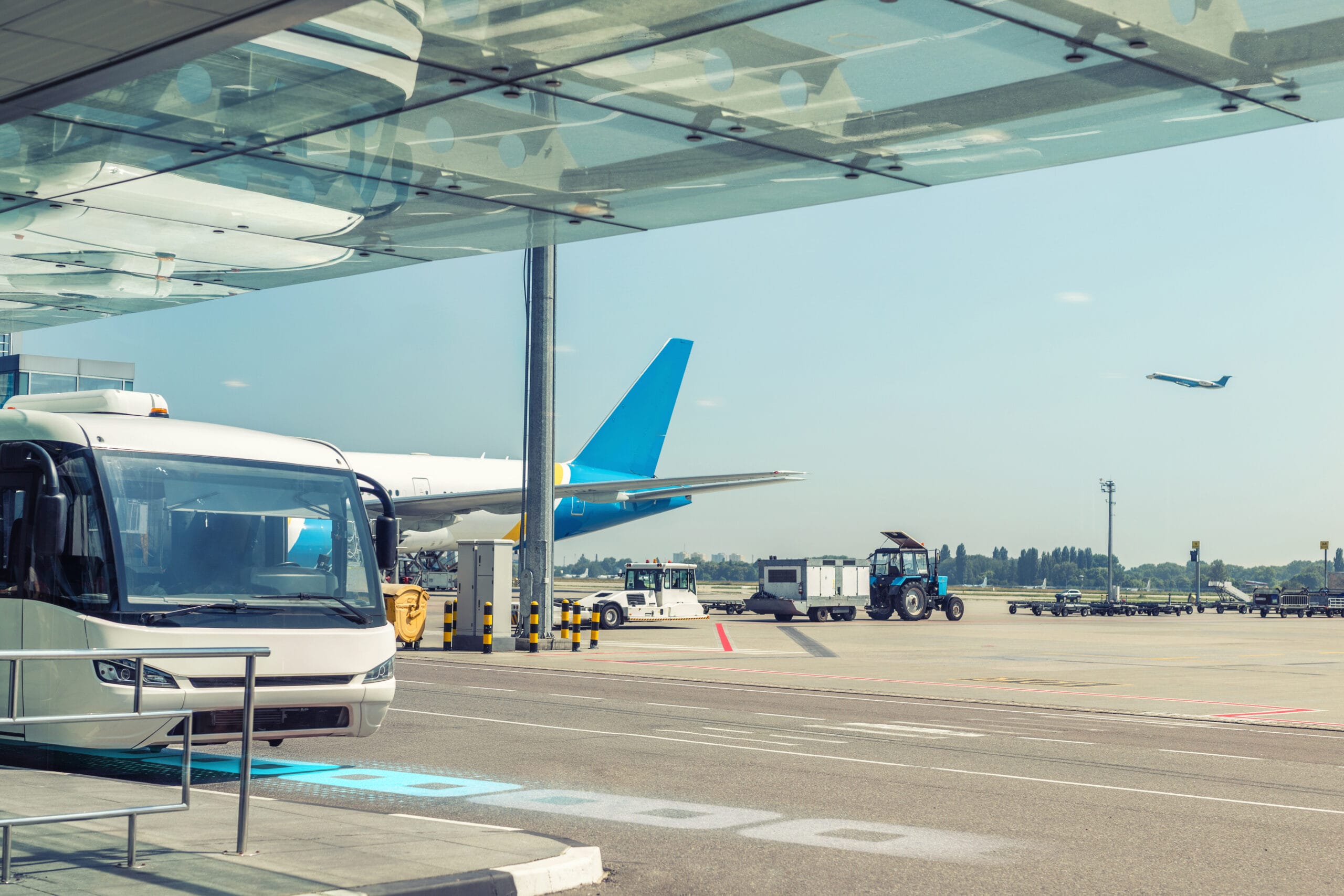 Airport environment and services. Shuttle bus waiting for passengers at terminal building. Big commercial plane on airfield. aircraft departure on background. Travel and tourist destination concept